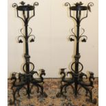 Pair of C19th style wrought iron fire dogs, with brazier basket finials on scroll, mask, ring and