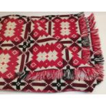 Vintage Welsh woolen blanket in red, black, white and grey geometric pattern, with attached label '