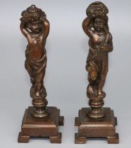 Pair of patinated bronze models of standing cherubs supporting flower filled cornucopia, on