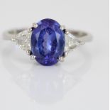 Platinum three stone tanzanite and diamond ring, the central oval cut tanzanite flanked by two