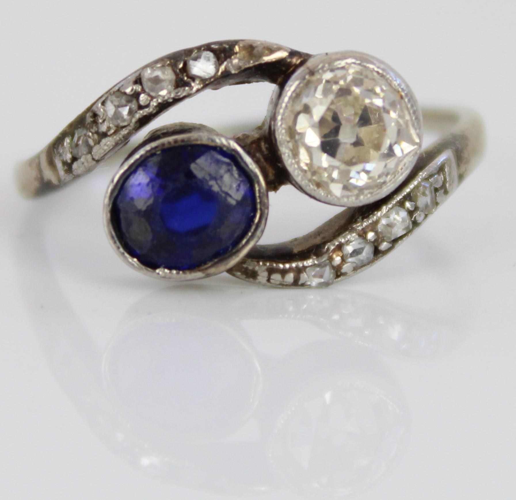 White metal diamond and sapphire crossover ring, the round cut diamond and oval cut sapphire in