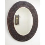 C20th oval wall mirror, bevelled plate in oak frame carved with Yorkshire Rose and leafage, H77cm