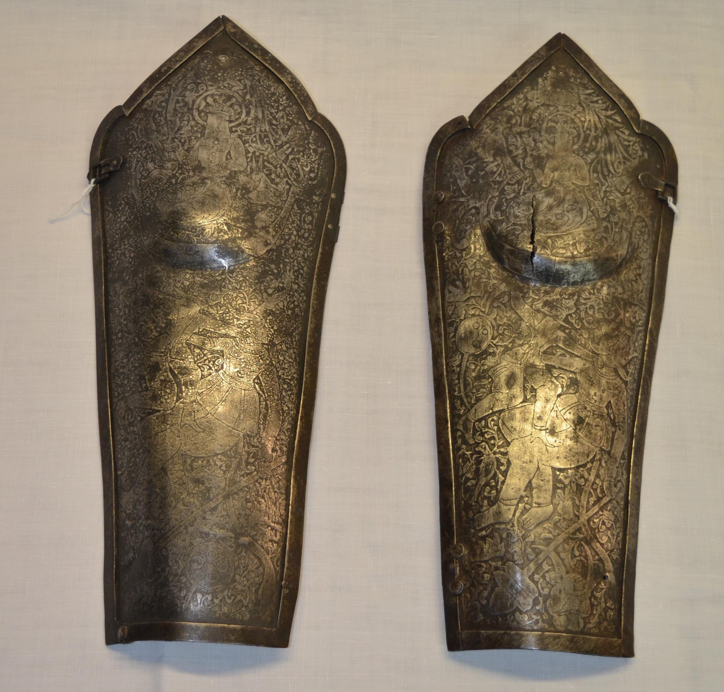 Pair of Indo-Persian c.C17th iron lower leg guards with engraved detail of fighting figures with - Image 2 of 4