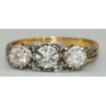 18ct yellow gold and platinum three stone diamond ring, the central round cut diamond in platinum