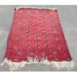 C20th Caucasian pattern red ground rug, central field with twenty seven oval medallions within a