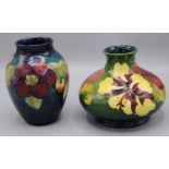 Moorcroft Pottery: Hibiscus design squat form vase, yellow and purple flowers on green ground,