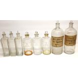 Collection of eight various Apothecary or Chemists clear glass bottles, titled in white and on paper