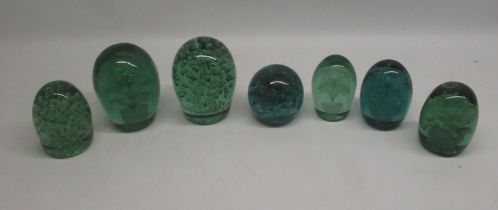 Group of seven green glass dumps, four with internal flowers, max H13cm. a/f
