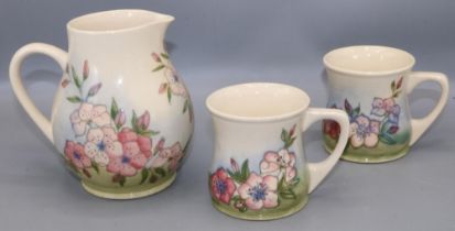 Moorcroft Pottery: Spring Blossom pattern jug and two mugs, tube lined decoration of pink flowers on