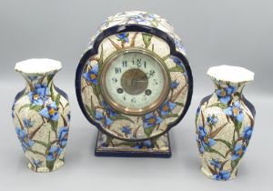 A. D. Mougin late C19th French three piece glazed pottery clock garniture, the moulded drum head