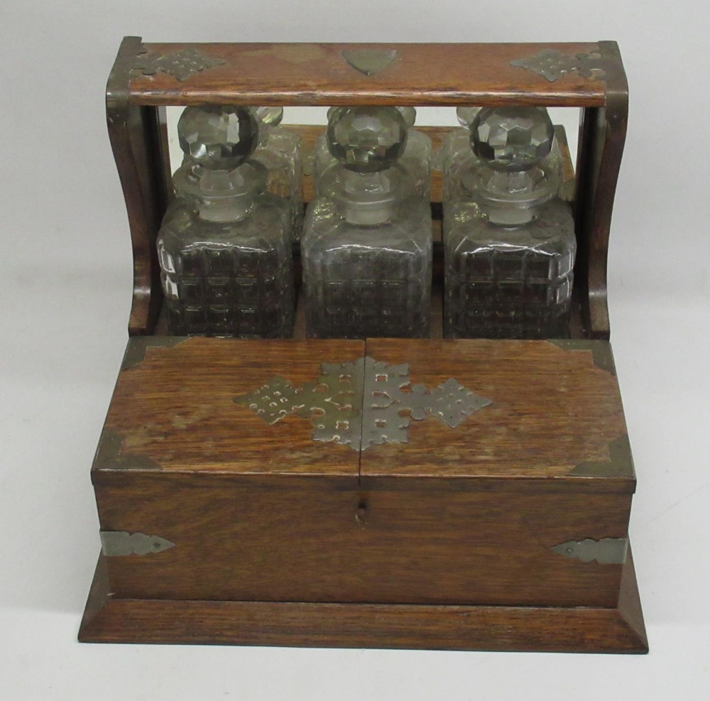 Early C20th three decanter oak tantalus with plated mounts and games compartment W38cm