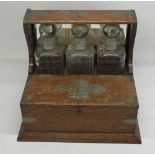 Early C20th three decanter oak tantalus with plated mounts and games compartment W38cm