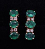 Yellow metal emerald and diamond earrings, each set with three oval cut emeralds and four diamonds