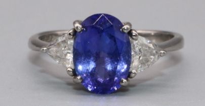 Platinum three stone tanzanite and diamond ring, the central oval cut tanzanite flanked by two