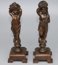 Pair of patinated bronze models of standing cherubs supporting flower filled cornucopia, on