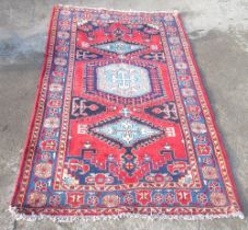 Red ground Caucasian rug with hooked triple lozenge medallion field in multi striped border, 260cm x