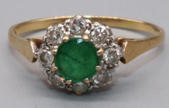 18ct yellow gold emerald and diamond cluster ring, the central circular faceted cut emerald