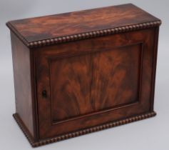 Early C19th figured mahogany table top key cupboard, with panel door and bead mouldings, interior