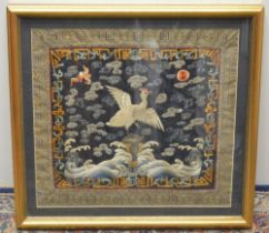 C19th Japanese silkwork panel, worked with a flying Crane and bats in clouds on a blue ground, in