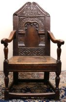 C17th style oak wainscot arm chair, arched panel back with scale carved angular top rail bearing