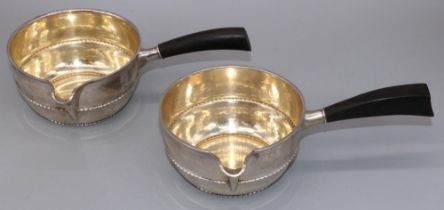 Pair of C20th Danish silver brandy pans circular bodies with spouts, beaded bands and black bakelite