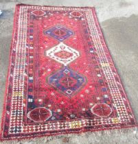 Multicoloured Shiraz rug, triple hooked medallion in red ground field with elephant foot spandrels