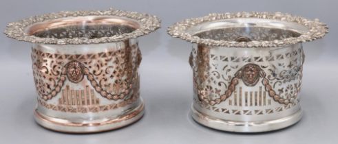 Pair of EP on copper Champagne bottle coasters, pierced bodies with lion masks and swags, scroll