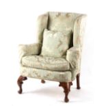 Property of a deceased estate - a George II style upholstered wing armchair, with carved cabriole
