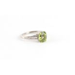 An 18ct white gold peridot & diamond ring, the oval cushion cut peridot weighing approximately 2.