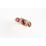An 18ct yellow gold ruby & diamond ring, with three oval cushion cut rubies in unusual crossover
