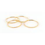 Property of a lady - a set of four matching 22ct gold (tested) bangles, with bright-cut flowerhead