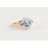 An 18ct yellow gold sapphire & diamond cluster ring, the round cut sapphire weighing an estimated