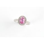 A platinum pink sapphire & diamond oval cluster ring, the oval cushion cut pink sapphire weighing