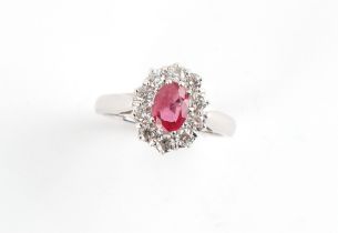 An 18ct white gold ruby & diamond oval cluster ring, the oval cushion cut ruby weighing