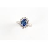 A platinum Ceylon sapphire & diamond oval cluster ring, the oval cushion cut sapphire weighing
