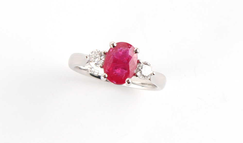 A platinum ruby & diamond three stone ring, the oval cushion cut ruby weighing approximately 1.51