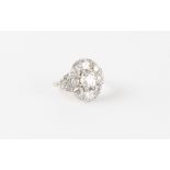 A good Belle Epoque style diamond cluster ring, the centre oval cushion cut diamond weighing