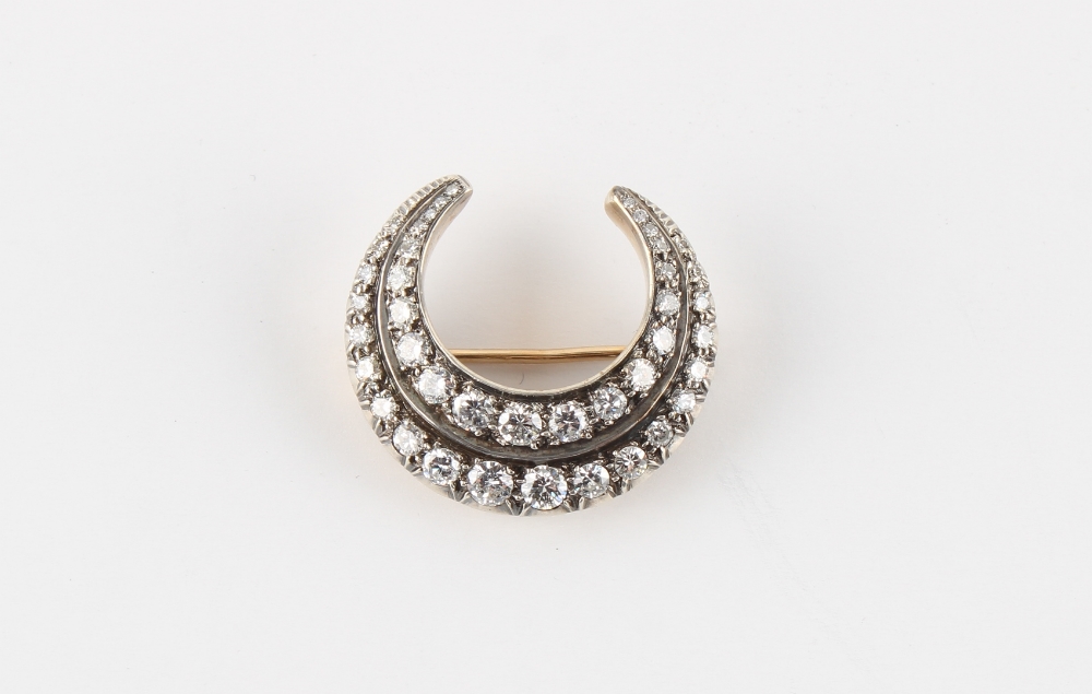 An unusual diamond double row crescent brooch, the round brilliant cut diamonds weighing a total