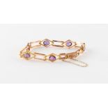 An early 20th century 9ct gold oval cut amethyst bracelet, the box clasp with engraved initials 'L.