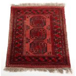 Property of a deceased estate - an Afghan rug, with red ground, 55 by 43ins. (140 by 109cms.).