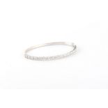 An 18ct white gold diamond hinged bangle, with seventeen round brilliant cut diamonds alternating