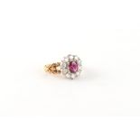 An unmarked good grade yellow gold ruby & diamond cluster ring, the oval cushion cut ruby weighing