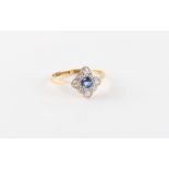 An 18ct yellow gold sapphire & diamond ring, the round cut sapphire set within a border of round cut
