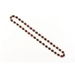 A 9ct gold garnet riviere necklace, the oval cut garnets in closed back settings, 16.75ins. (42.