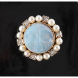 A carved moonstone diamond & pearl circular brooch, the circular moonstone carved with a face,