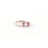 An unusual 18ct white gold ruby & diamond buckle ring, set with 9 square cut diamonds set within a