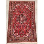 Property of a gentleman - a Persian hand-knotted wool rug with red field, 67 by 41ins. (170 by