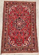 Property of a gentleman - a Persian hand-knotted wool rug with red field, 67 by 41ins. (170 by