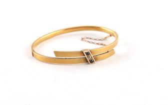 A late Victorian 15ct gold hinged bangle set with a single round cut diamond flanked by two round