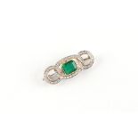 An unmarked white & yellow gold emerald & diamond interlinking loops brooch, the emerald weighing